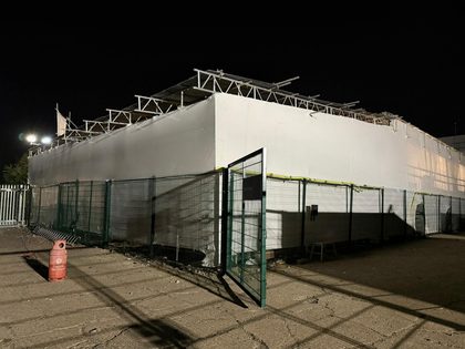 Scaffold-built temporary structure fully enclosed in shrink wrap and lit at night